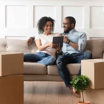 Smiling black couple use digital tablet on moving day